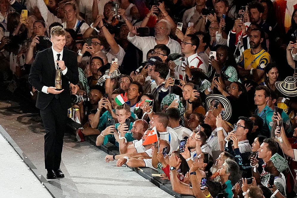 | Photo: AP/Rebecca Blackwell : Paris Olympics: French swimmer Leon Marchand carries a lantern containing the Olympic flame